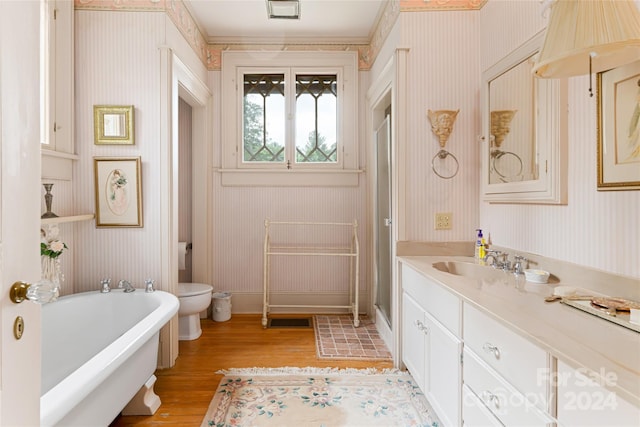 bathroom with toilet, a bath, hardwood / wood-style flooring, and vanity