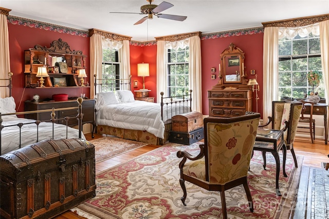 bedroom with hardwood / wood-style flooring, multiple windows, ornamental molding, and ceiling fan