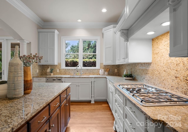 kitchen with light stone countertops, backsplash, stainless steel gas cooktop, sink, and white cabinetry