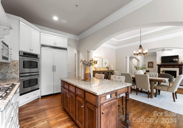 kitchen with backsplash, light stone countertops, appliances with stainless steel finishes, decorative light fixtures, and white cabinetry