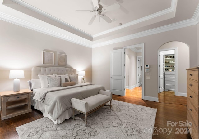 bedroom featuring a tray ceiling, ceiling fan, dark hardwood / wood-style flooring, and ornamental molding