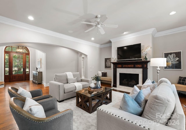 living room featuring ceiling fan with notable chandelier, light hardwood / wood-style floors, and ornamental molding