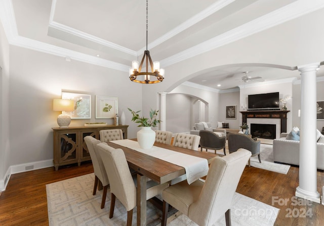 dining space featuring a raised ceiling, ceiling fan with notable chandelier, crown molding, and dark wood-type flooring