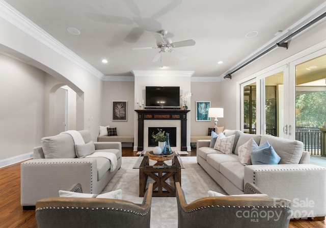 living room with light wood-type flooring, ceiling fan, and ornamental molding