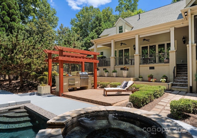 view of patio with ceiling fan, a swimming pool with hot tub, and exterior kitchen