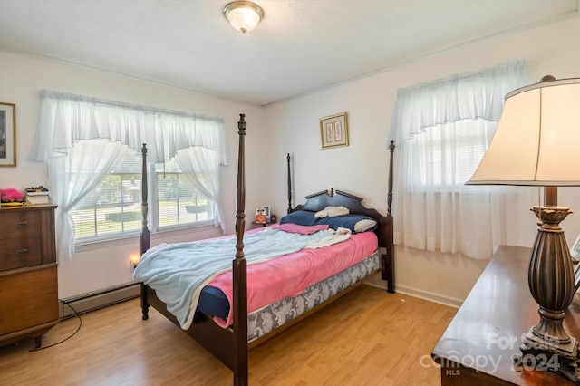 bedroom featuring a baseboard radiator, multiple windows, and light hardwood / wood-style floors