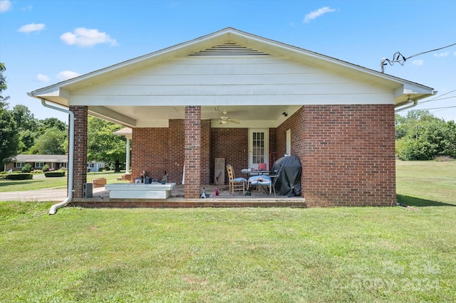 rear view of house with ceiling fan and a yard