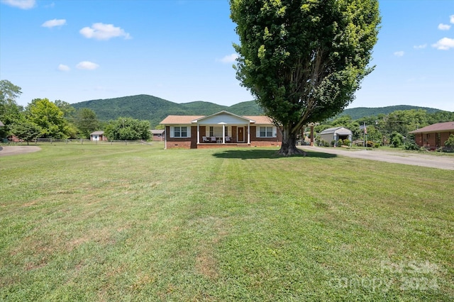 single story home featuring a mountain view, a porch, and a front yard