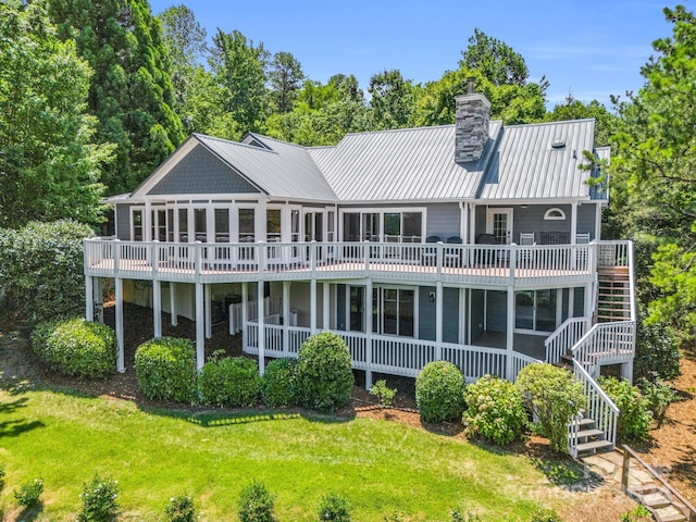 back of property with a lawn, a wooden deck, and a sunroom