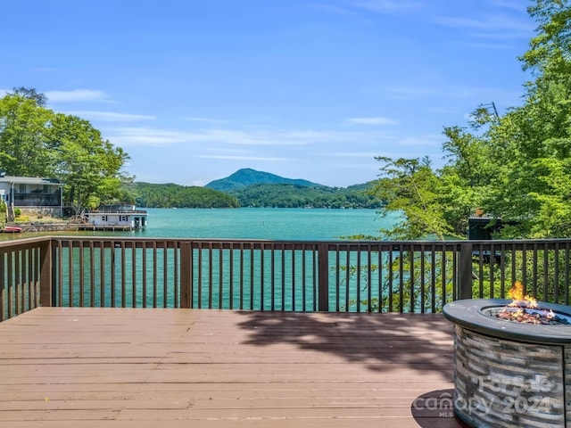 wooden deck with a water and mountain view and a fire pit