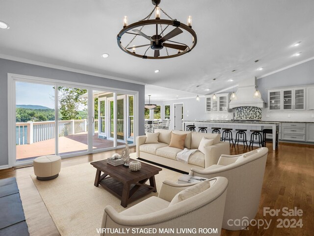 living room featuring lofted ceiling, an inviting chandelier, crown molding, and hardwood / wood-style flooring