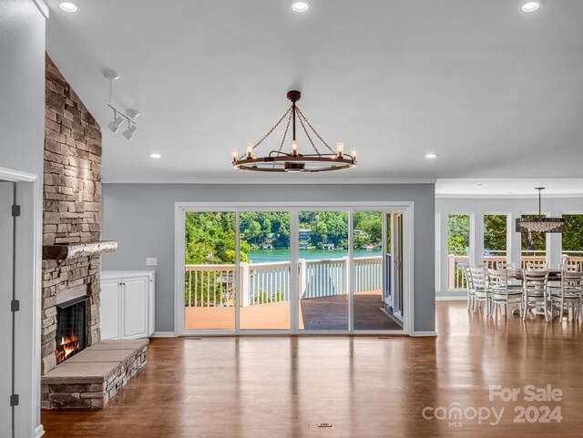 unfurnished living room featuring vaulted ceiling, a notable chandelier, a stone fireplace, and hardwood / wood-style flooring