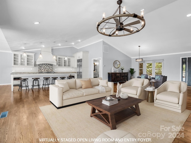 living room with light hardwood / wood-style floors, a chandelier, and vaulted ceiling