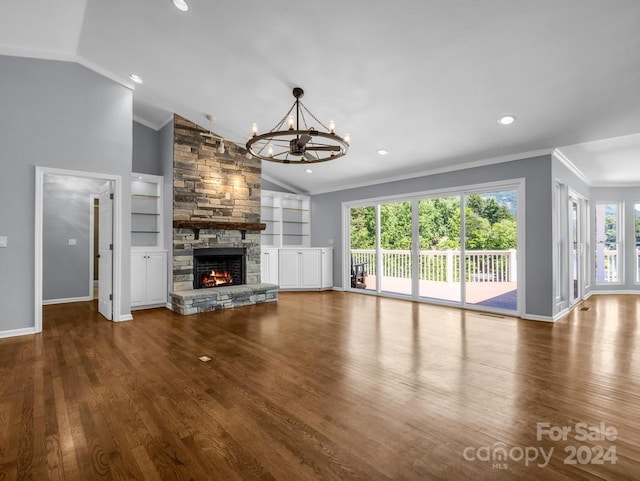 unfurnished living room featuring hardwood / wood-style flooring, a notable chandelier, a fireplace, vaulted ceiling, and built in shelves