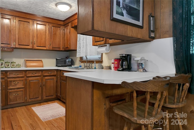 kitchen featuring a kitchen breakfast bar, sink, light hardwood / wood-style flooring, and kitchen peninsula