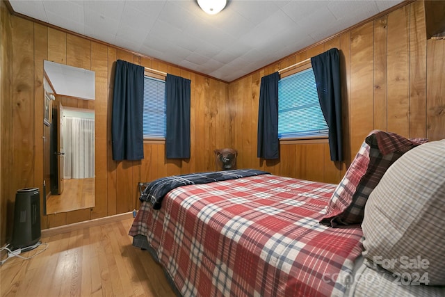 bedroom with wood walls and light hardwood / wood-style floors