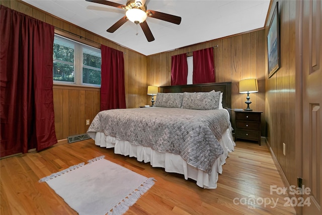 bedroom featuring ceiling fan, wooden walls, and light hardwood / wood-style floors