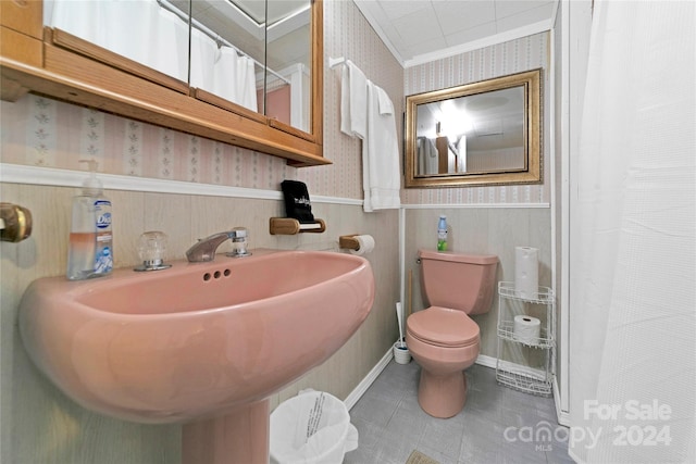 bathroom featuring toilet, a shower with shower curtain, crown molding, and sink