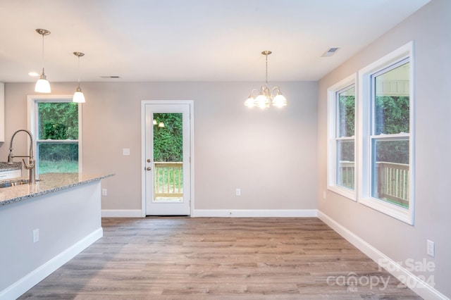 unfurnished dining area featuring a chandelier, light hardwood / wood-style floors, and sink