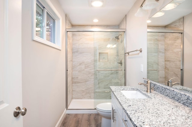 bathroom featuring toilet, vanity, an enclosed shower, and hardwood / wood-style flooring