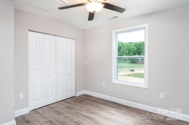 unfurnished bedroom with light wood-type flooring, ceiling fan, and a closet