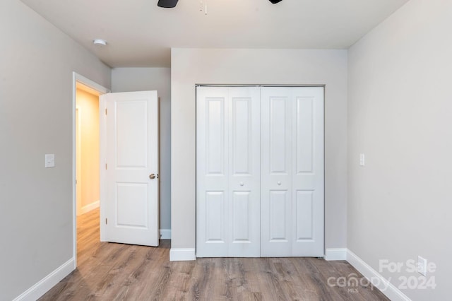 unfurnished bedroom featuring ceiling fan, a closet, and light wood-type flooring