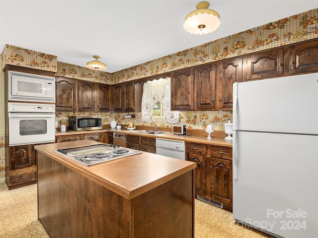 kitchen with dark brown cabinetry, sink, stainless steel appliances, and a kitchen island