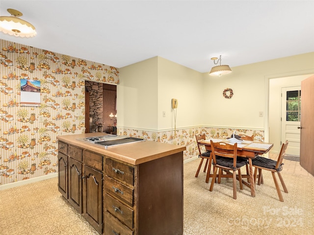 kitchen with decorative light fixtures, stainless steel gas cooktop, a center island, and dark brown cabinetry