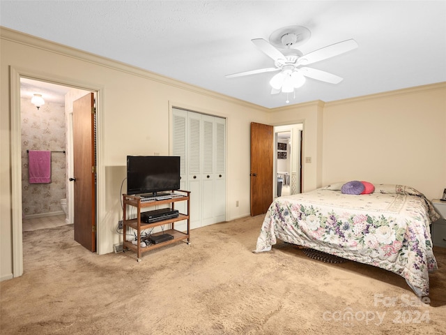 bedroom featuring ceiling fan, ornamental molding, light colored carpet, and ensuite bath