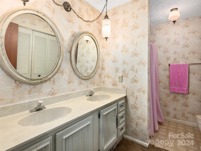 bathroom with toilet, vanity, tile patterned floors, and a textured ceiling