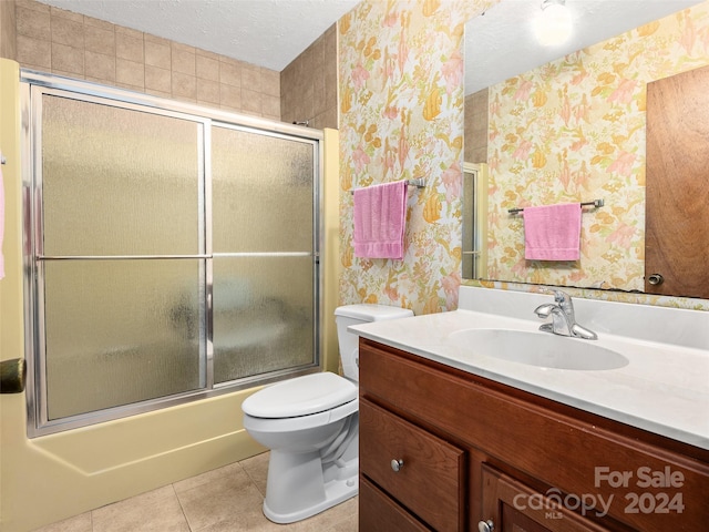 full bathroom featuring a textured ceiling, enclosed tub / shower combo, tile patterned floors, vanity, and toilet