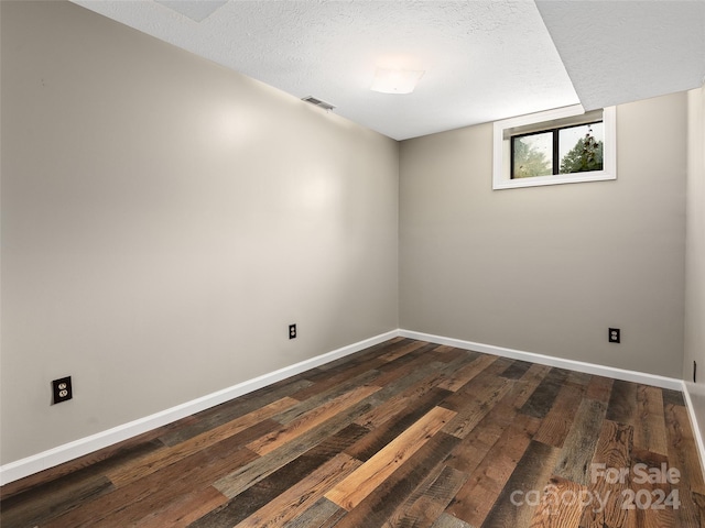 empty room with dark wood-type flooring and a textured ceiling