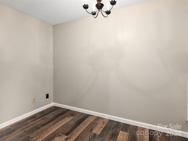 unfurnished room with dark wood-type flooring and a notable chandelier