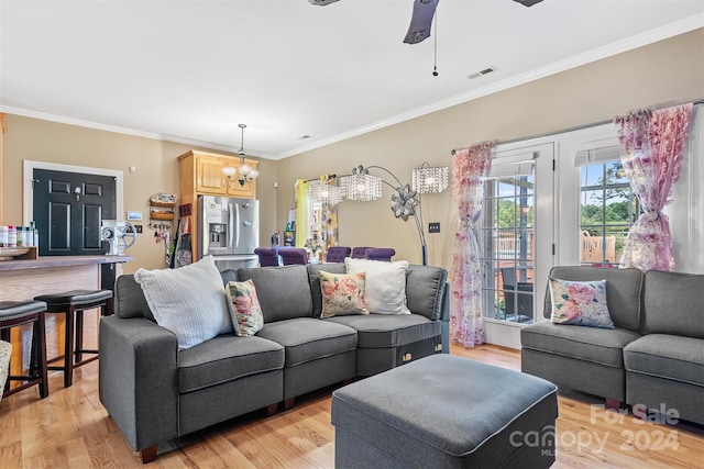 living room with ceiling fan with notable chandelier, crown molding, and light hardwood / wood-style flooring