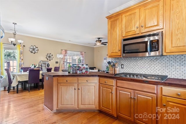 kitchen with light hardwood / wood-style floors, plenty of natural light, ornamental molding, and stainless steel appliances