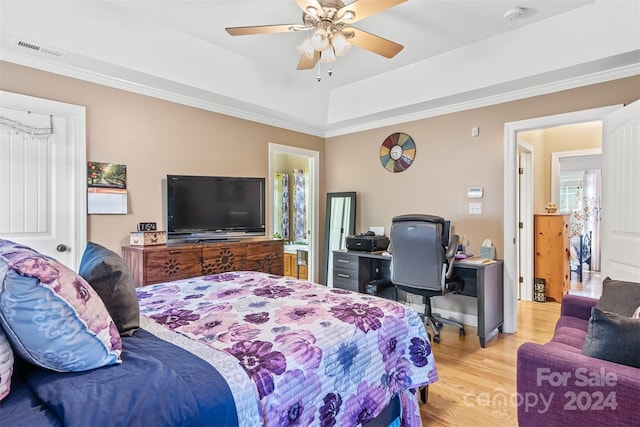 bedroom featuring ceiling fan, ornamental molding, a raised ceiling, and light wood-type flooring