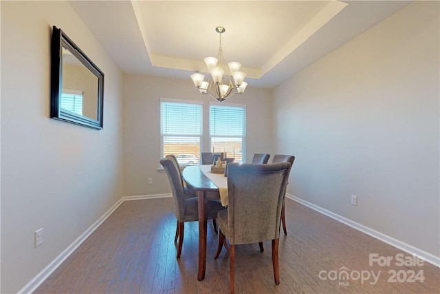 dining space featuring hardwood / wood-style floors, a notable chandelier, and a tray ceiling