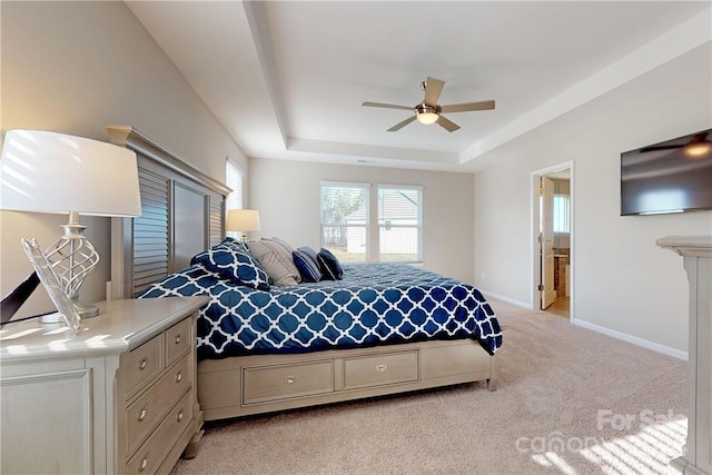 carpeted bedroom featuring ceiling fan, connected bathroom, and a tray ceiling