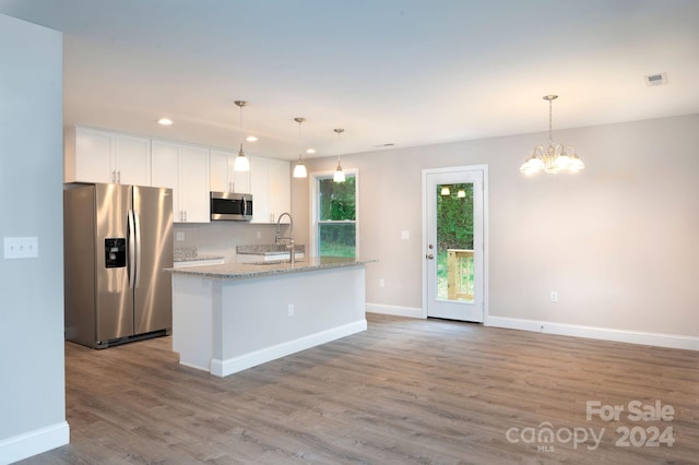 kitchen with white cabinets, a kitchen island with sink, appliances with stainless steel finishes, and pendant lighting