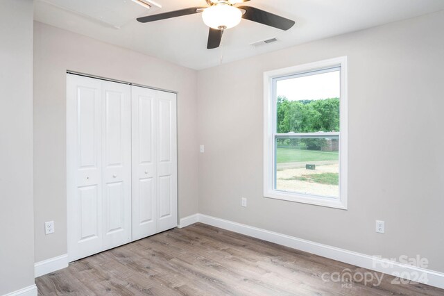 unfurnished bedroom with ceiling fan, a closet, and light wood-type flooring