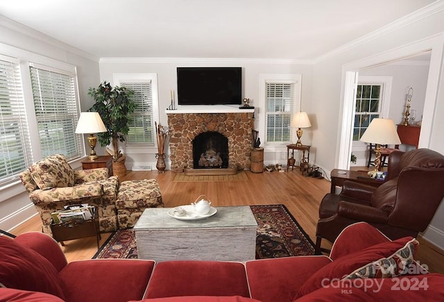 living room featuring a stone fireplace, ornamental molding, and hardwood / wood-style flooring