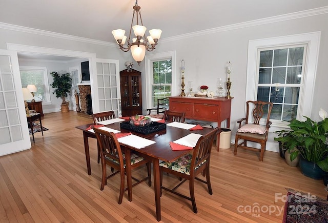 dining space featuring light wood-type flooring, a chandelier, and crown molding