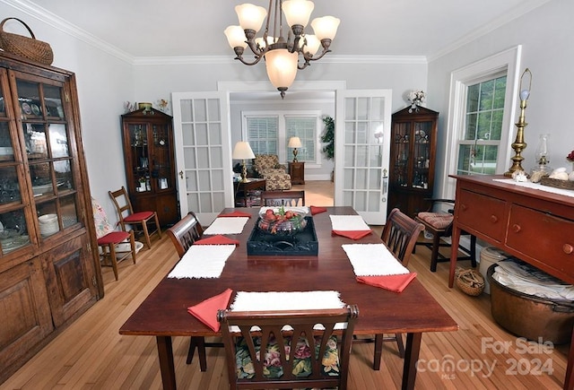 dining area with french doors, a notable chandelier, crown molding, and light hardwood / wood-style flooring