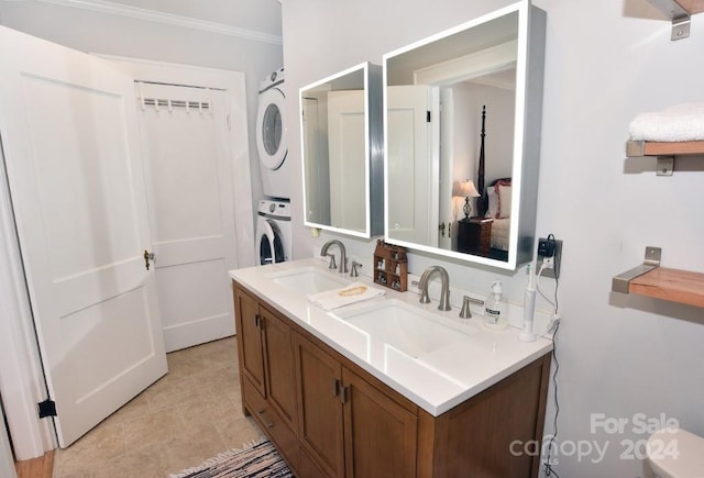 bathroom with vanity, stacked washer and dryer, tile patterned floors, and crown molding