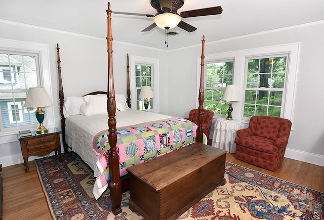 bedroom with ceiling fan, multiple windows, hardwood / wood-style floors, and ornamental molding