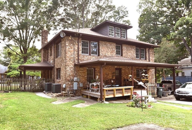 back of house with central AC unit, a wooden deck, and a lawn