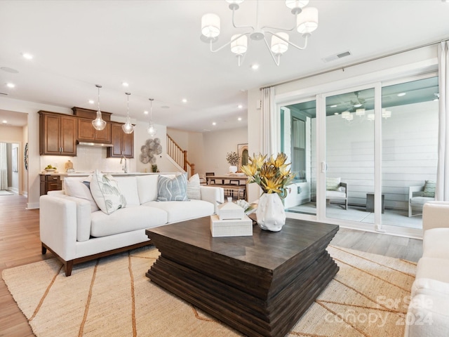 living room with an inviting chandelier, light hardwood / wood-style flooring, and sink