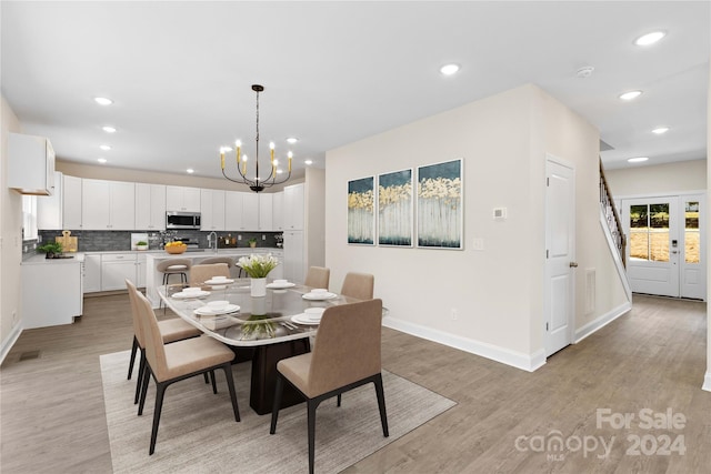 dining space with sink, a chandelier, and light hardwood / wood-style floors