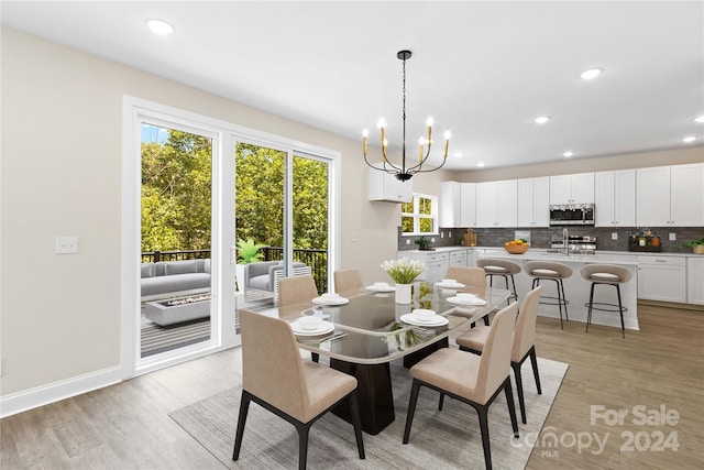 dining space featuring an inviting chandelier, sink, and light hardwood / wood-style floors