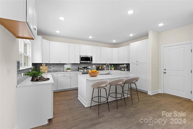 kitchen with sink, a breakfast bar, stainless steel appliances, an island with sink, and white cabinets